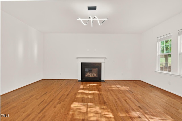 4518 Coral Dr, Durham, NC 27713 - unfurnished living room with light wood-style flooring, a chandelier, and a fireplace with flush hearth