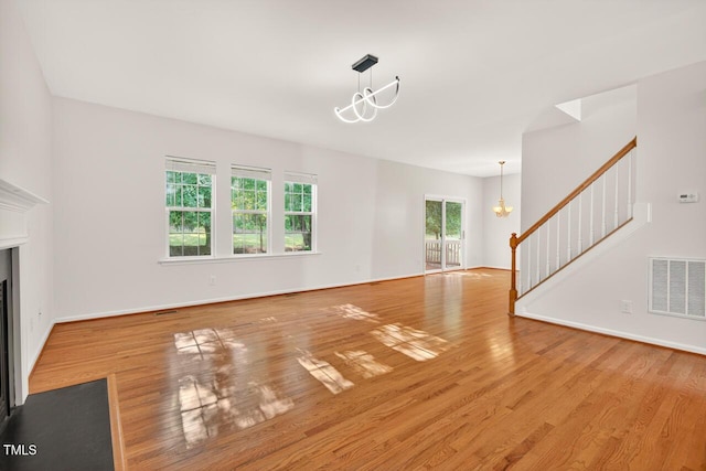 4518 Coral Dr, Durham, NC 27713 - unfurnished living room featuring a chandelier, stairs, wood finished floors, and a fireplace with flush hearth