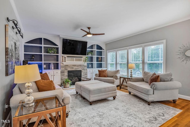 7269 Bedford Ridge Dr, Apex, NC 27539 - living area featuring ornamental molding, ceiling fan, a stone fireplace, wood finished floors, and built in features