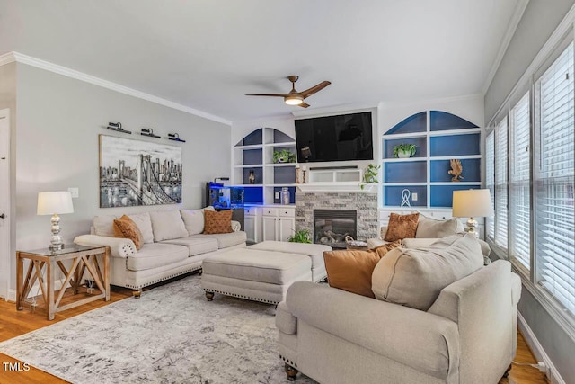 7269 Bedford Ridge Dr, Apex, NC 27539 - living room featuring ornamental molding, a ceiling fan, built in features, a stone fireplace, and wood finished floors