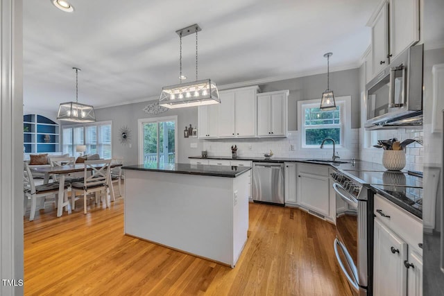 7269 Bedford Ridge Dr, Apex, NC 27539 - kitchen with stainless steel appliances, a kitchen island, light wood-style flooring, backsplash, and white cabinetry