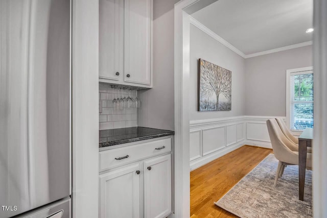 7269 Bedford Ridge Dr, Apex, NC 27539 - kitchen with ornamental molding, fridge, light wood-type flooring, dark countertops, and backsplash