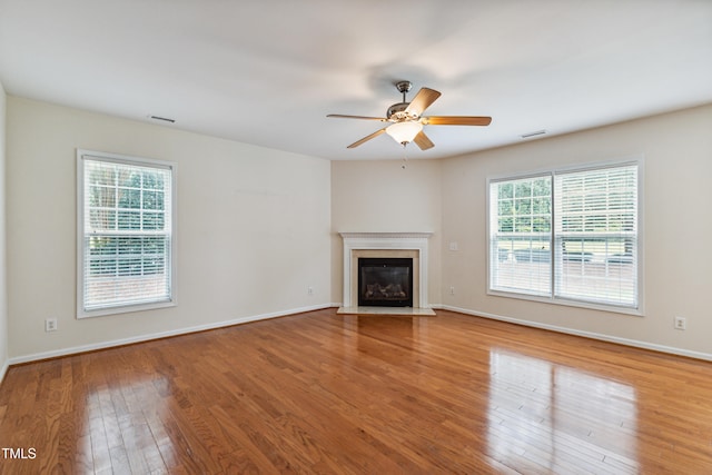 2228 Cedar Grove Dr, Durham, NC 27703 - unfurnished living room featuring plenty of natural light, wood finished floors, a glass covered fireplace, and a ceiling fan