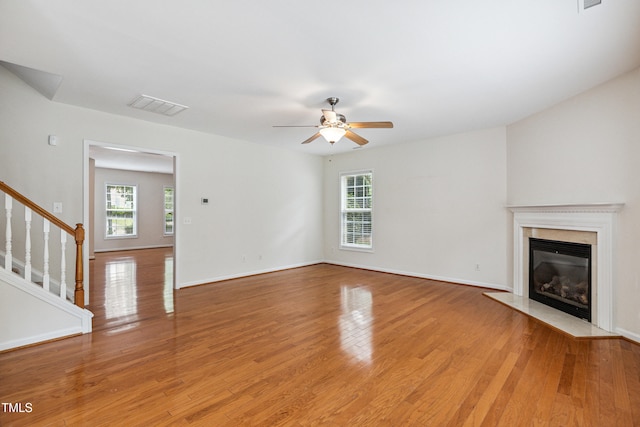 2228 Cedar Grove Dr, Durham, NC 27703 - unfurnished living room with ceiling fan, a premium fireplace, light wood finished floors, and stairs