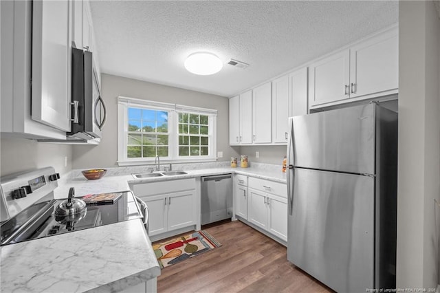 615 Wallingford Ct, Fayetteville, NC 28314 - kitchen featuring stainless steel appliances, white cabinets, wood finished floors, a textured ceiling, and light countertops