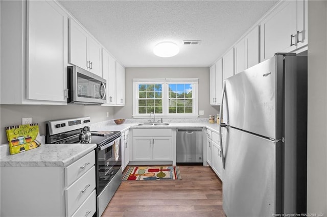 615 Wallingford Ct, Fayetteville, NC 28314 - kitchen with stainless steel appliances, wood finished floors, a textured ceiling, white cabinets, and light countertops