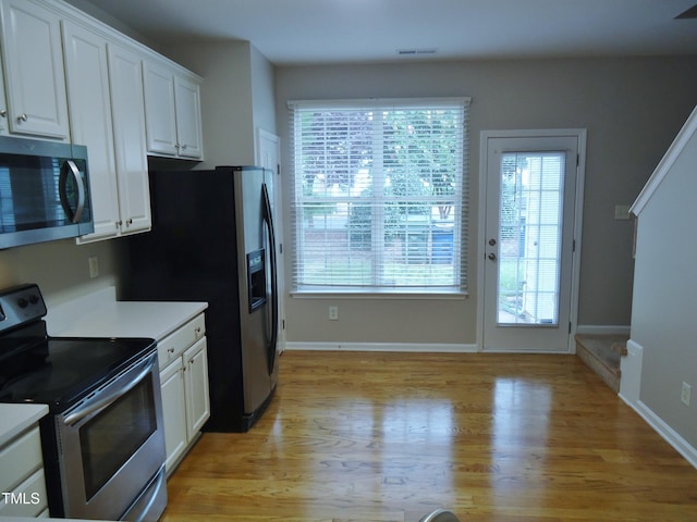 8315 City Loft Ct, Raleigh, NC 27613 - kitchen with appliances with stainless steel finishes, white cabinetry, healthy amount of natural light, and light wood finished floors