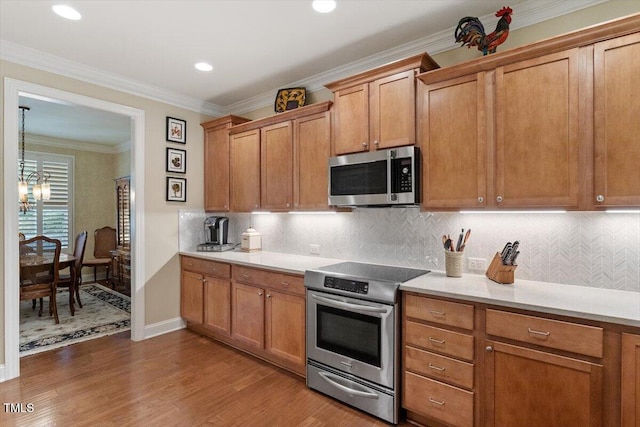 2800 Royal Forrest Dr, Raleigh, NC 27614 - kitchen with appliances with stainless steel finishes, wood finished floors, brown cabinetry, a chandelier, and crown molding