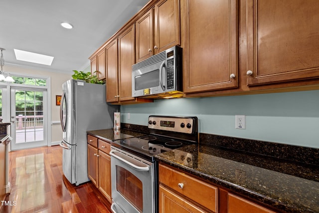 430 Beechwood Trl, Henderson, NC 27536 - kitchen featuring appliances with stainless steel finishes, a skylight, dark wood finished floors, brown cabinets, and recessed lighting