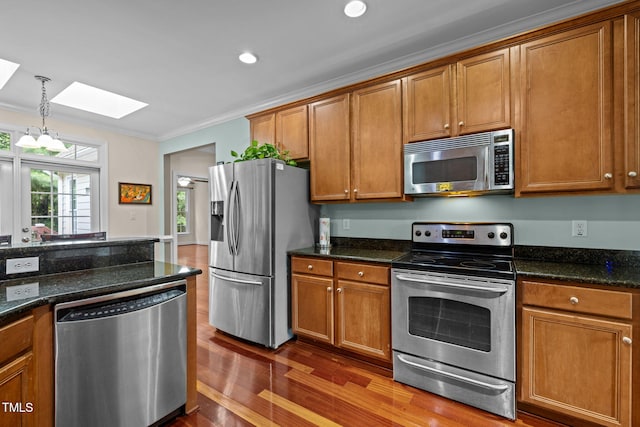 430 Beechwood Trl, Henderson, NC 27536 - kitchen with appliances with stainless steel finishes, a skylight, brown cabinets, dark wood-style flooring, and ornamental molding
