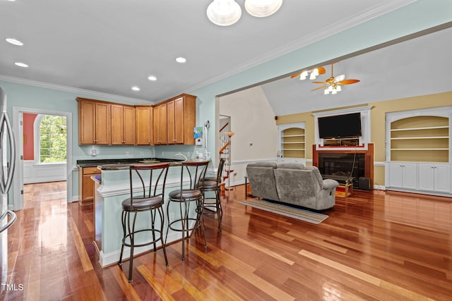 430 Beechwood Trl, Henderson, NC 27536 - kitchen with wood finished floors, a breakfast bar, built in shelves, dark countertops, and ornamental molding
