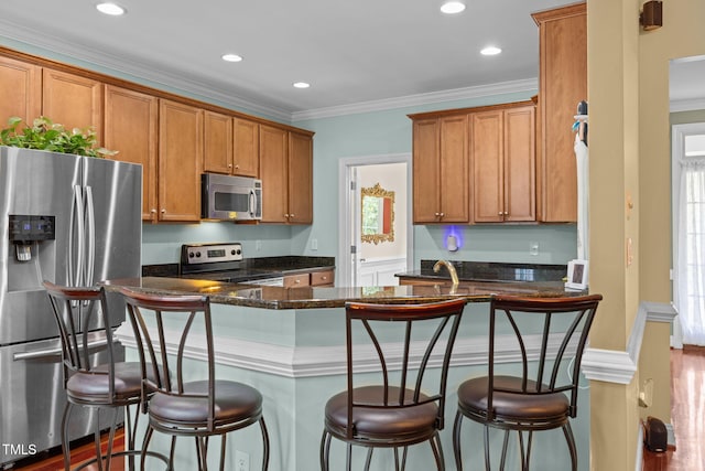 430 Beechwood Trl, Henderson, NC 27536 - kitchen with appliances with stainless steel finishes, brown cabinetry, a breakfast bar, dark stone counters, and ornamental molding