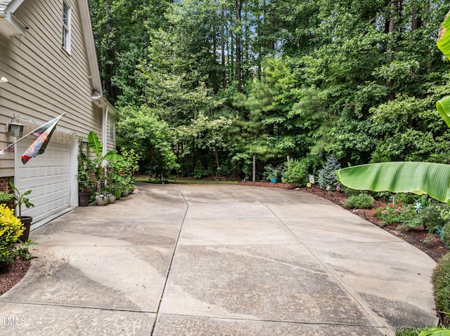 430 Beechwood Trl, Henderson, NC 27536 - view of patio with driveway, an attached garage, and view of scattered trees