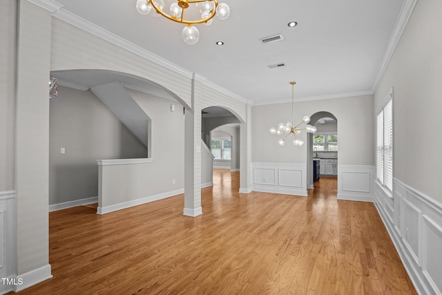 111 Court Jester Way, Morrisville, NC 27560 - unfurnished dining area featuring a chandelier, arched walkways, ornamental molding, light wood-style flooring, and wainscoting