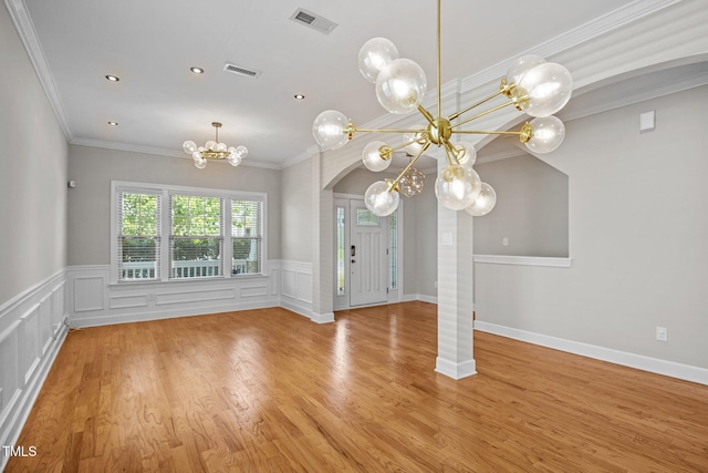 111 Court Jester Way, Morrisville, NC 27560 - unfurnished living room with a chandelier, arched walkways, light wood-style flooring, ornamental molding, and wainscoting