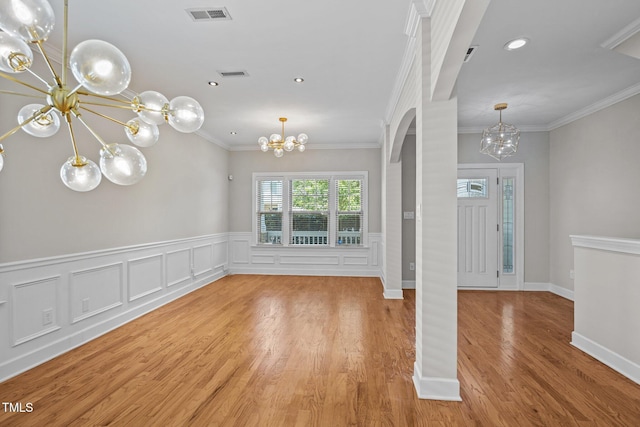 111 Court Jester Way, Morrisville, NC 27560 - unfurnished dining area with a chandelier, arched walkways, ornamental molding, a wainscoted wall, and wood finished floors