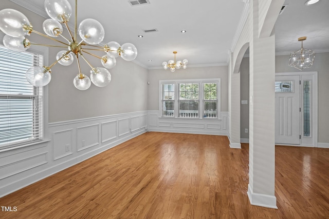 111 Court Jester Way, Morrisville, NC 27560 - unfurnished dining area with a chandelier, arched walkways, ornamental molding, a wainscoted wall, and wood finished floors