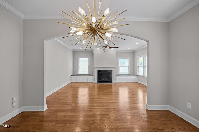 111 Court Jester Way, Morrisville, NC 27560 - unfurnished living room featuring crown molding, wood finished floors, a chandelier, arched walkways, and a fireplace with flush hearth