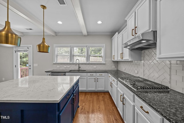 111 Court Jester Way, Morrisville, NC 27560 - kitchen with under cabinet range hood, blue cabinets, stainless steel gas stovetop, beamed ceiling, and white cabinets