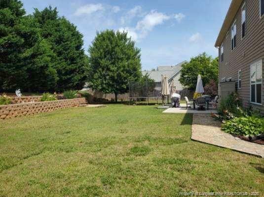 5724 Avera Ln, Holly Springs, NC 27540 - view of green lawn with a trampoline and a patio area