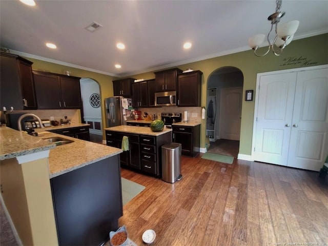 5724 Avera Ln, Holly Springs, NC 27540 - kitchen with arched walkways, appliances with stainless steel finishes, light stone counters, light wood-style flooring, and crown molding