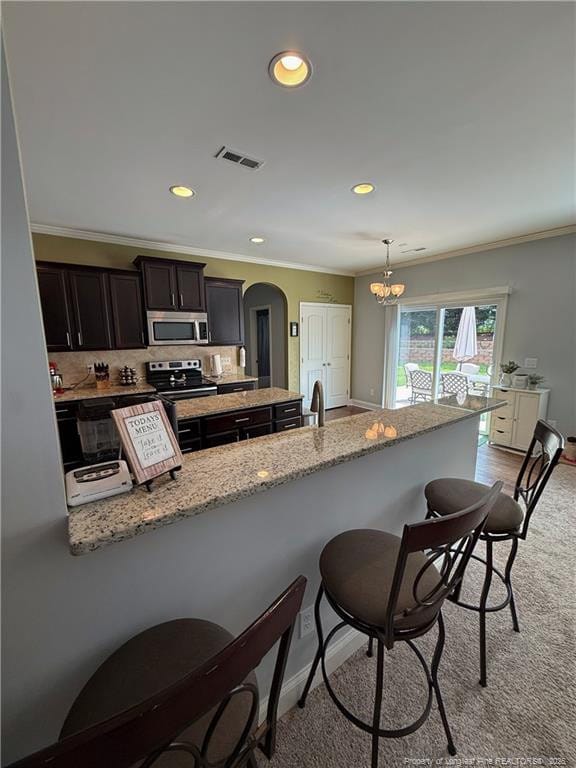 5724 Avera Ln, Holly Springs, NC 27540 - kitchen with appliances with stainless steel finishes, a kitchen bar, crown molding, light carpet, and light stone counters