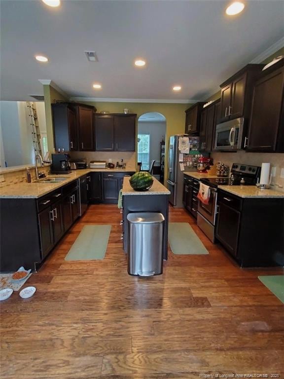 5724 Avera Ln, Holly Springs, NC 27540 - kitchen featuring stainless steel appliances, ornamental molding, arched walkways, wood finished floors, and a center island