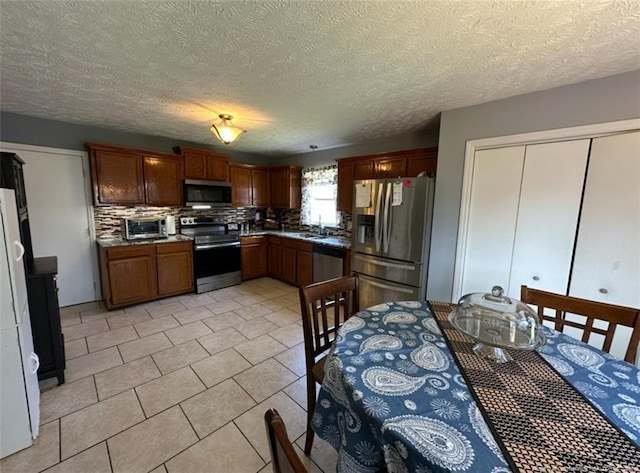 7453 Avila Dr, Fayetteville, NC 28314 - kitchen featuring stainless steel appliances, decorative backsplash, a textured ceiling, and light tile patterned flooring