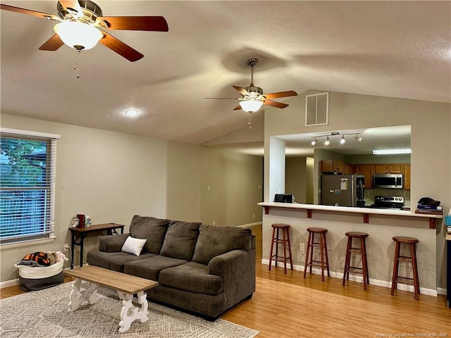 6622 Vaughn Rd, Fayetteville, NC 28304 - living room with ceiling fan, light wood-style flooring, vaulted ceiling, and a textured ceiling