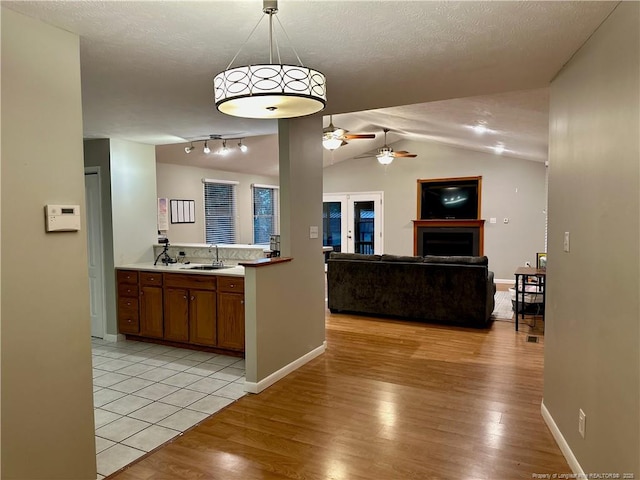 6622 Vaughn Rd, Fayetteville, NC 28304 - kitchen featuring ceiling fan, brown cabinetry, light wood-type flooring, light countertops, and vaulted ceiling