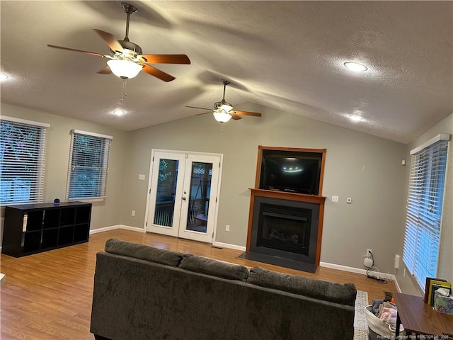 6622 Vaughn Rd, Fayetteville, NC 28304 - living room featuring ceiling fan, vaulted ceiling, wood finished floors, a fireplace with flush hearth, and french doors