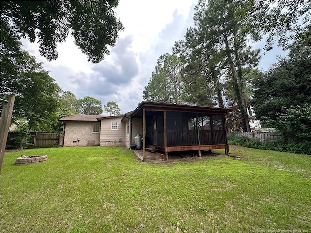 6622 Vaughn Rd, Fayetteville, NC 28304 - rear view of property featuring a sunroom, a fenced backyard, and an outdoor fire pit