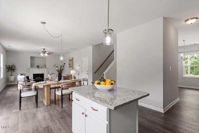 1643 Southcross St, Fuquay Varina, NC 27526 - kitchen featuring a fireplace, dark wood-style floors, a center island, ceiling fan, and white cabinets