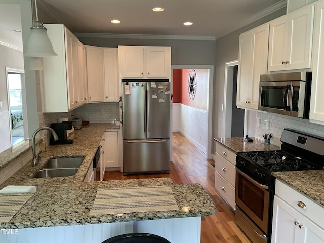 1034 Snapdragon Dr, Wake Forest, NC 27587 - kitchen featuring appliances with stainless steel finishes, light wood-style flooring, a peninsula, ornamental molding, and white cabinets