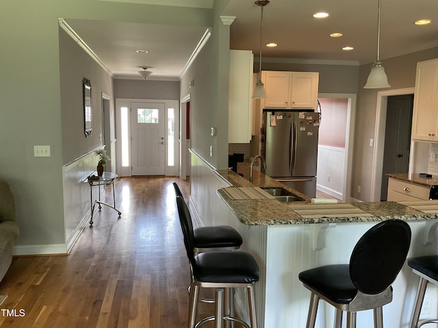 1034 Snapdragon Dr, Wake Forest, NC 27587 - kitchen featuring freestanding refrigerator, a breakfast bar area, ornamental molding, stone countertops, and white cabinetry