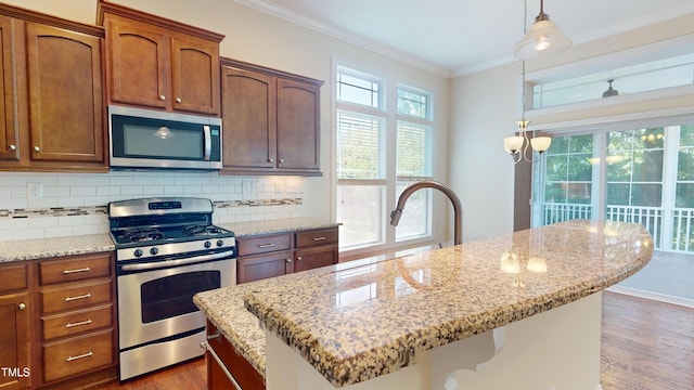 1524 Lily Creek Dr, Cary, NC 27518 - kitchen featuring appliances with stainless steel finishes, ornamental molding, wood finished floors, tasteful backsplash, and a center island