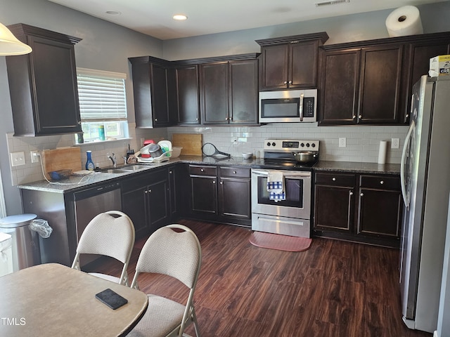 1303 Salters St, Burlington, NC 27215 - kitchen featuring stainless steel appliances, dark wood-type flooring, dark stone countertops, dark brown cabinetry, and recessed lighting