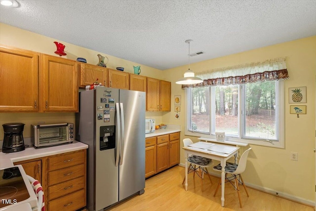 4201 Pin Oak Dr, Durham, NC 27707 - kitchen with stainless steel refrigerator with ice dispenser, stove, brown cabinets, a textured ceiling, and light wood-type flooring