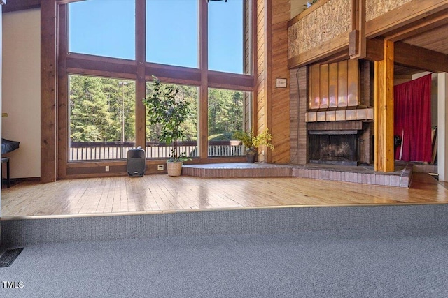 4201 Pin Oak Dr, Durham, NC 27707 - living room featuring a brick fireplace, hardwood / wood-style floors, a towering ceiling, and wood walls
