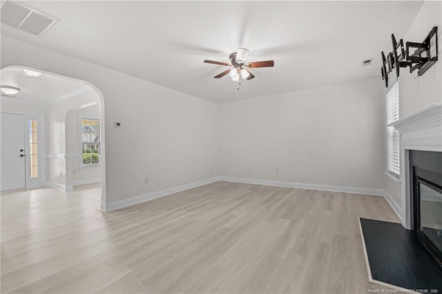 297 Colonist Pl, Cameron, NC 28326 - unfurnished living room with arched walkways, a ceiling fan, light wood-style floors, and a glass covered fireplace