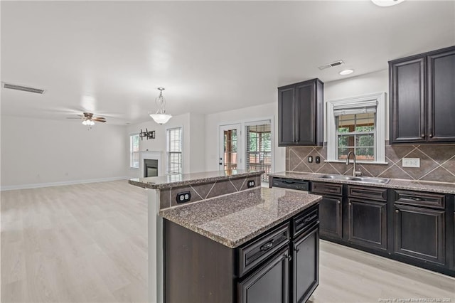 297 Colonist Pl, Cameron, NC 28326 - kitchen with light wood-type flooring, a kitchen island, stone counters, tasteful backsplash, and dishwasher