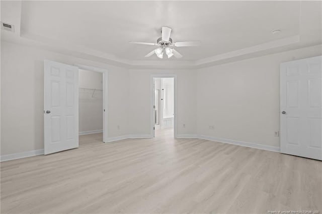 297 Colonist Pl, Cameron, NC 28326 - unfurnished bedroom with a tray ceiling, light wood-type flooring, and a spacious closet