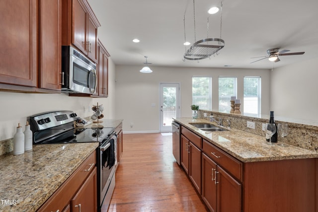 130 Holly Berry Ln, Durham, NC 27703 - kitchen with stainless steel appliances, light wood-style flooring, ceiling fan, light stone counters, and a center island with sink