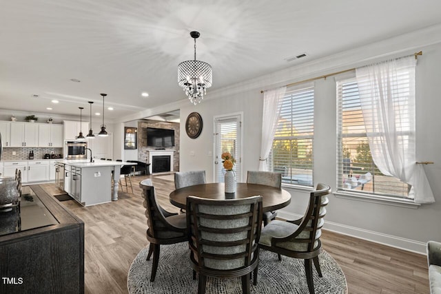 27 Needham Ln, Clayton, NC 27527 - dining room with ornamental molding, a fireplace, light wood finished floors, a chandelier, and recessed lighting