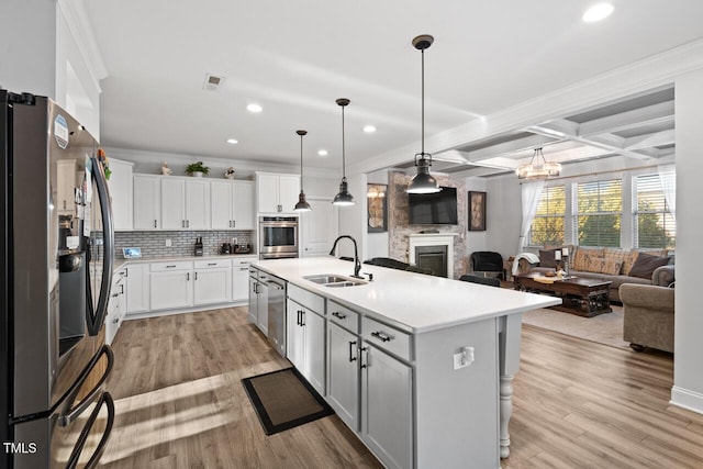 27 Needham Ln, Clayton, NC 27527 - kitchen featuring appliances with stainless steel finishes, open floor plan, a glass covered fireplace, light countertops, and decorative backsplash