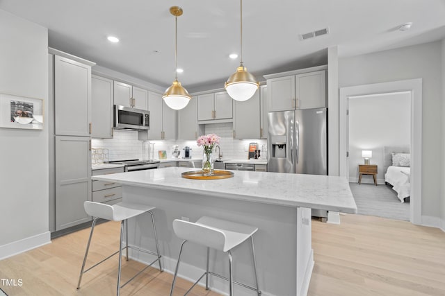 105 Chatham Walk Ln Unit 208, Cary, NC 27511 - kitchen featuring appliances with stainless steel finishes, a kitchen bar, light wood-style floors, decorative backsplash, and recessed lighting