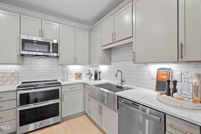 105 Chatham Walk Ln Unit 208, Cary, NC 27511 - kitchen featuring stainless steel appliances, light stone counters, backsplash, and light wood-style floors