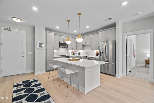105 Chatham Walk Ln Unit 208, Cary, NC 27511 - kitchen featuring stainless steel appliances, light wood-style flooring, a kitchen breakfast bar, tasteful backsplash, and a kitchen island
