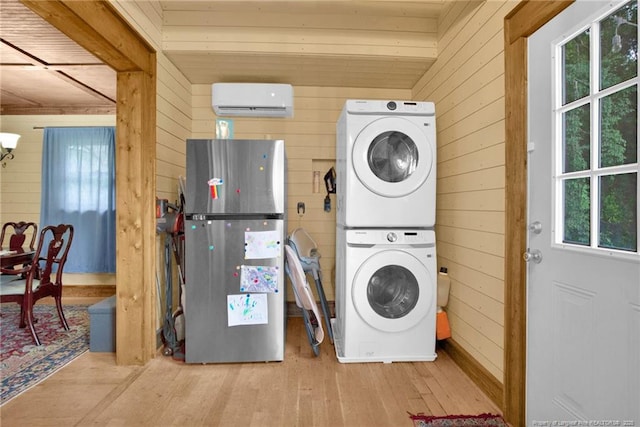 1203 Simpson St, Fayetteville, NC 28305 - laundry room featuring stacked washer / dryer, an AC wall unit, wooden walls, wood-type flooring, and plenty of natural light