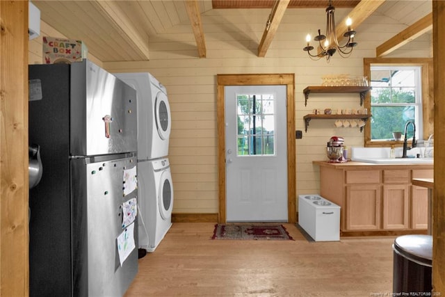 1203 Simpson St, Fayetteville, NC 28305 - kitchen featuring freestanding refrigerator, stacked washing machine and dryer, light wood-style floors, healthy amount of natural light, and wooden walls
